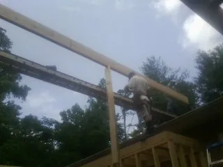 Carpenter setting a ridge beam over a new addition frame — Ice Dam Removal by Roofing Brothers in Virgin