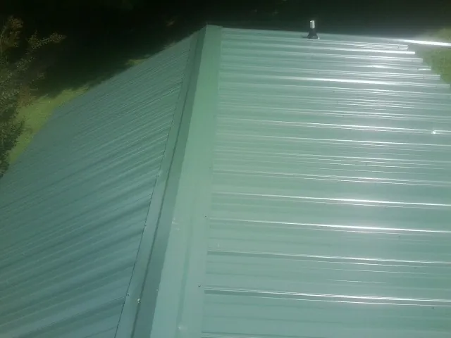 New green metal panels meeting at the ridge of a roof — Flat Roof Repair work by our crew in Virgin