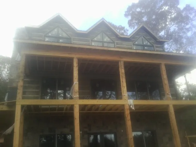 Dormers and porch framing on a large log home under construction — Roof Coating work by our crew in Virgin