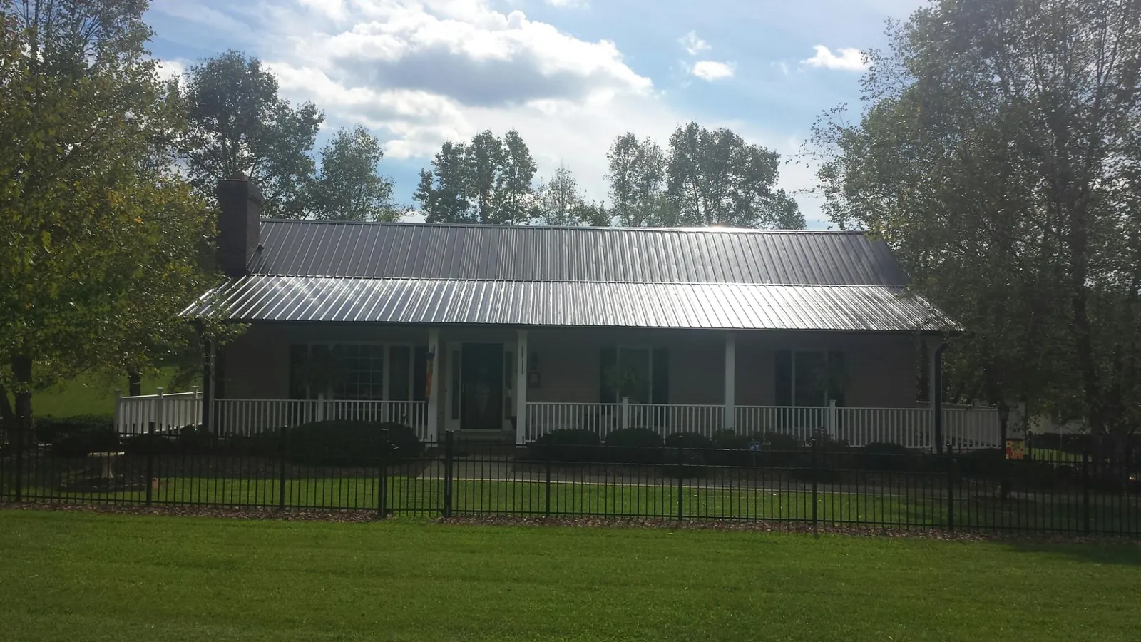 Gray metal roof on a brick ranch with a full width front porch — Gutter Guard Installation work by our crew in Virgin