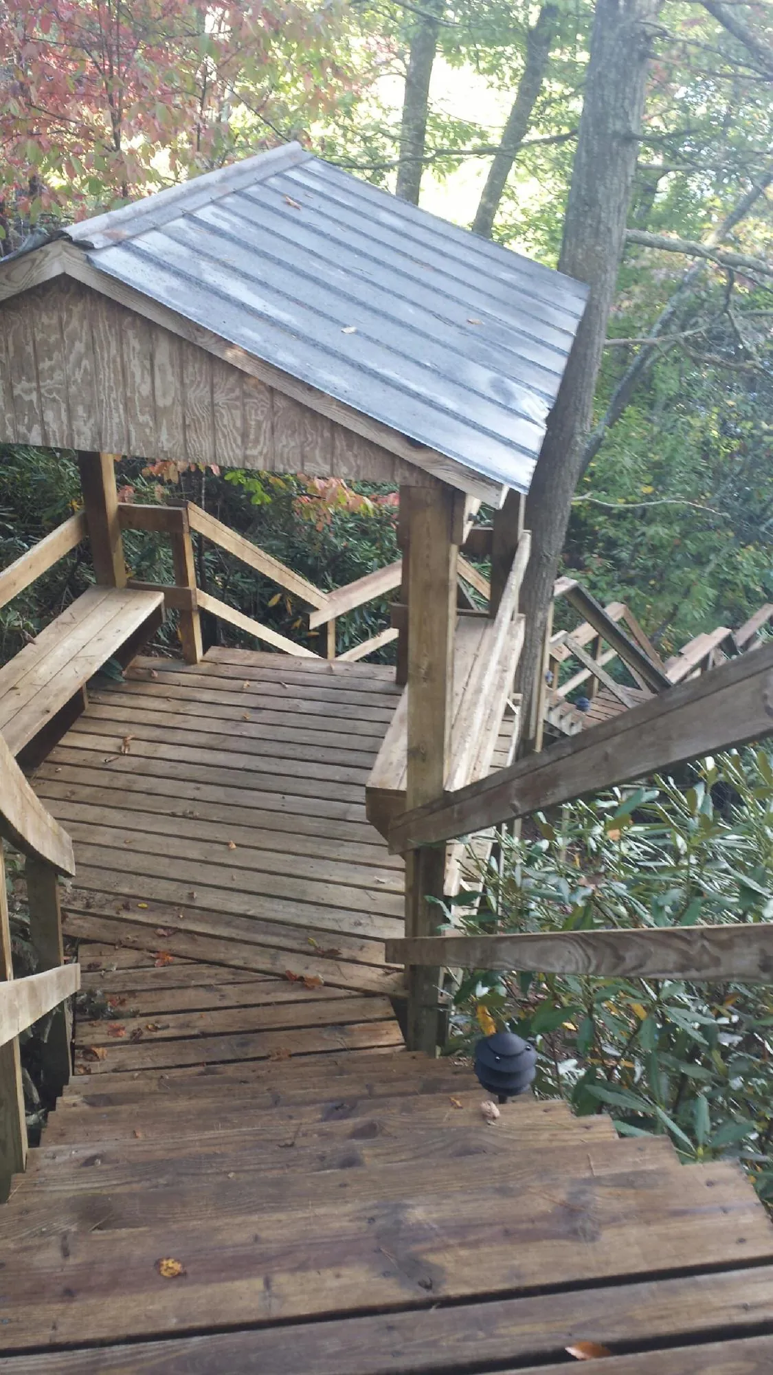 Metal roofed shelter over wooden steps on a wooded walkway — Skylight Repair & Installation work by our crew in Virgin