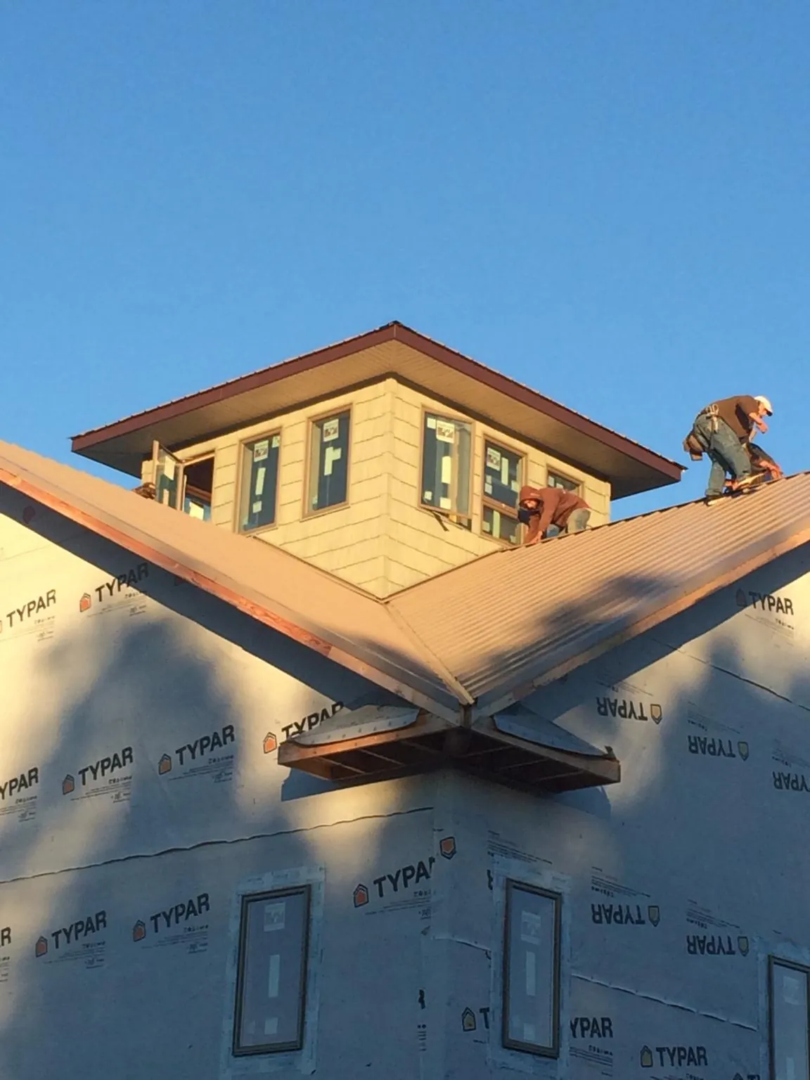 Roofers working around a rooftop cupola on a new metal roof at sunset — Roof Waterproofing in Virgin by Roofing Brothers